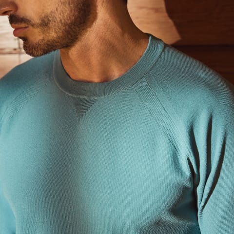 テックスブリッド クルーネックニットを着用している男性モデルの上半身アップ画像