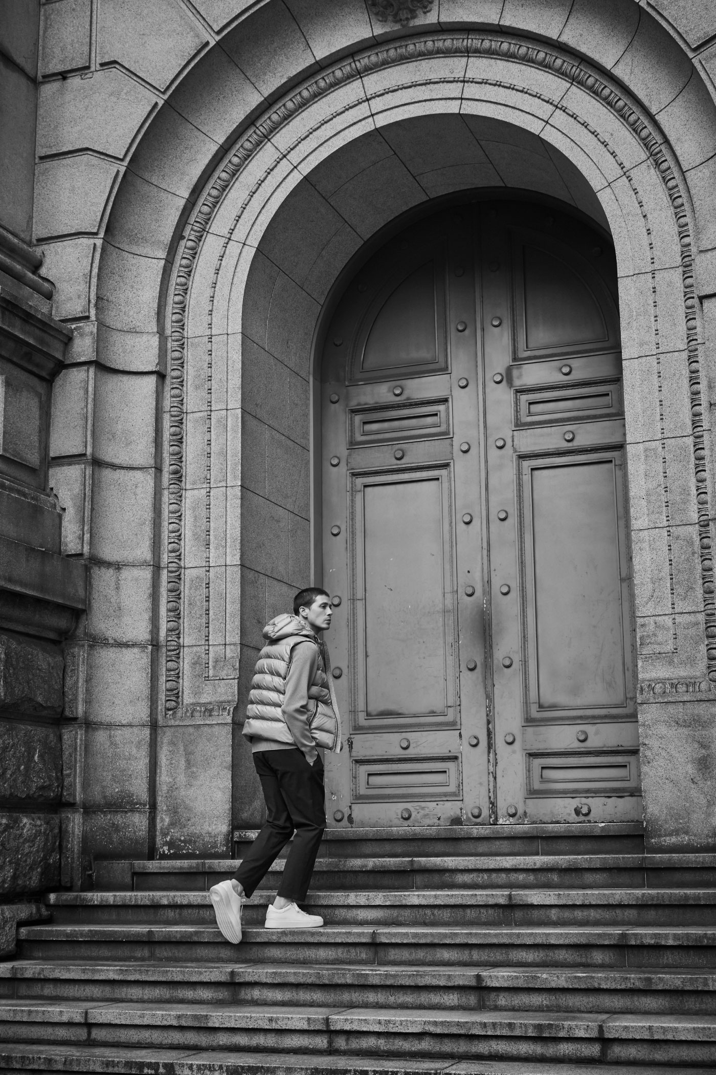 大きな門の前の階段を歩いている高身長の男性