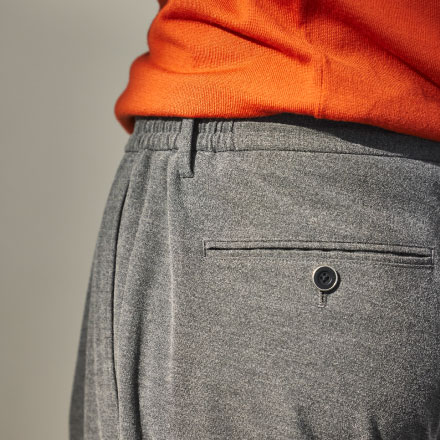 オレンジのニットとグレーのパンツを履いた男性