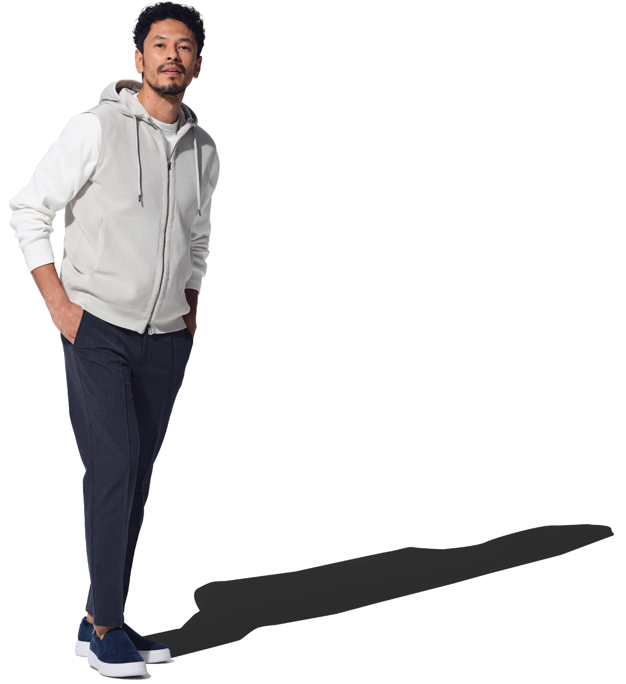 グレーのニットベスト・オフホワイトのトップス・ダークブルーのパンツ・ネイビーのスニーカーを着用した男性