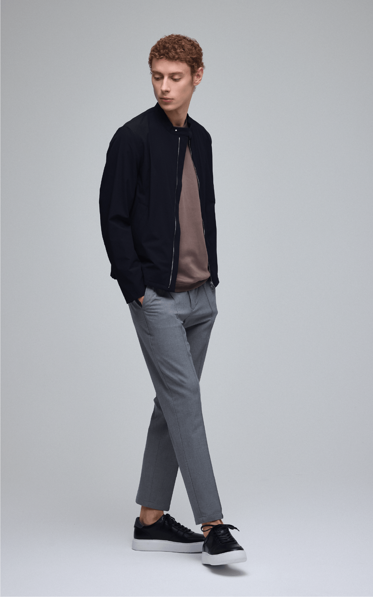 ブルゾン、ニット、パンツ、シューズを着用した男性
