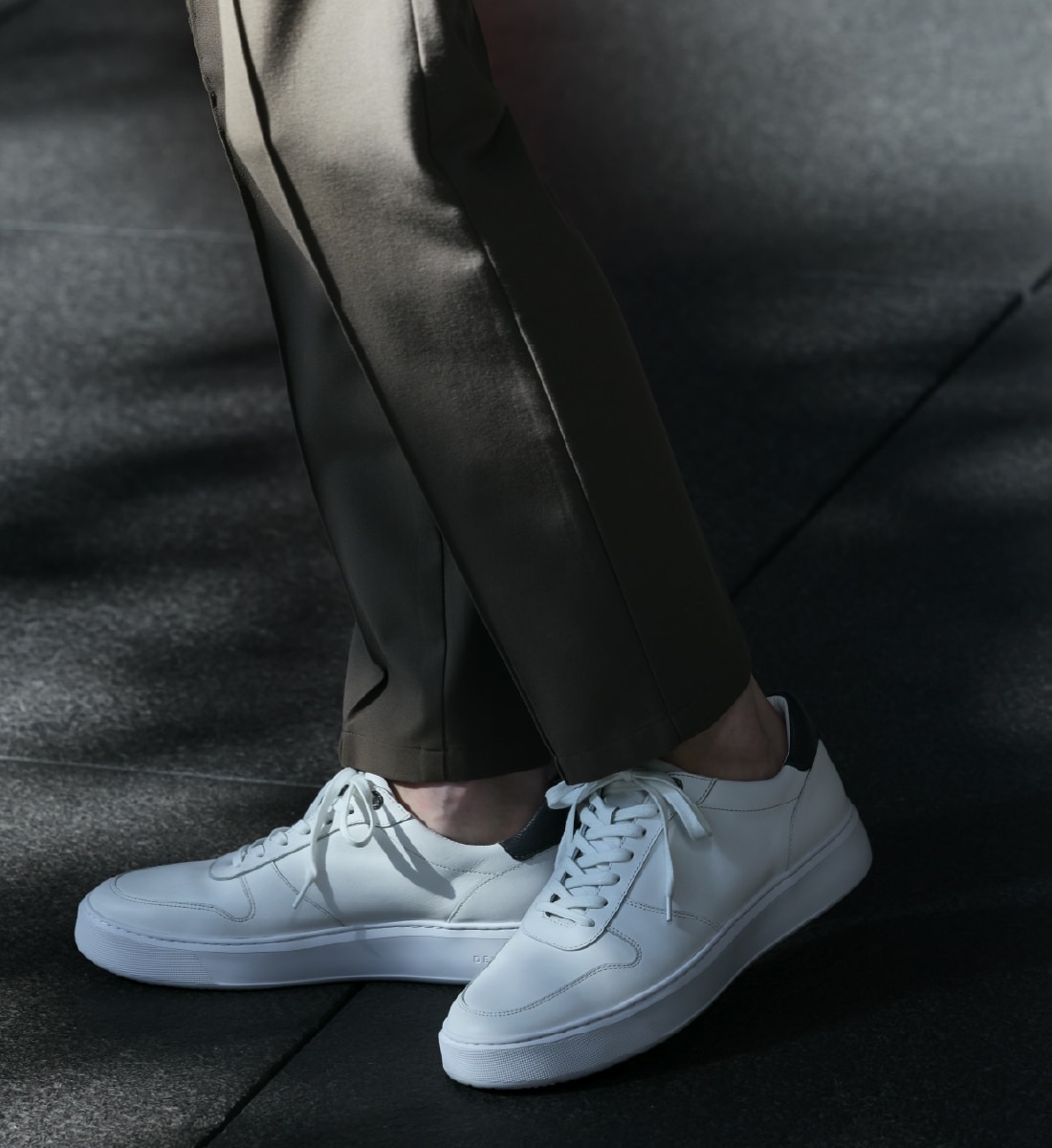 白のスニーカーとモカのボトムの足元写真
