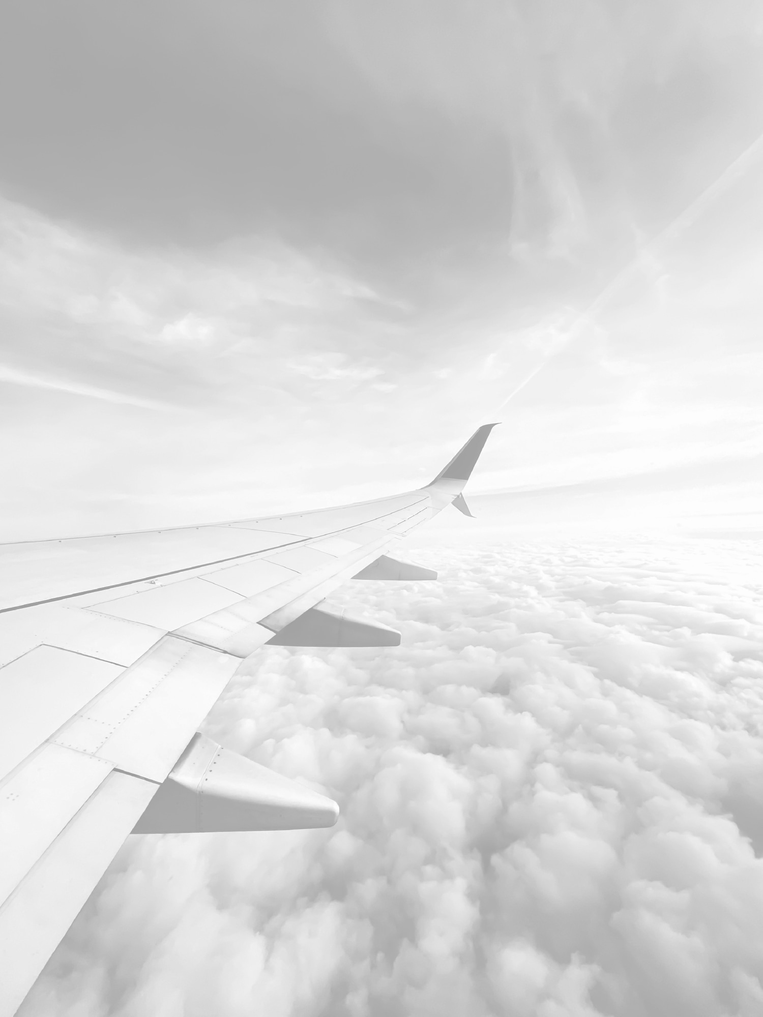 飛行機の機窓から見た主翼と雲のイメージ画像