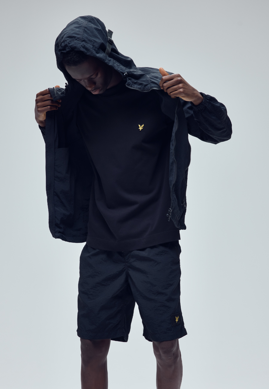 ブラックのTシャツ・ブラックのハーフパンツ・ブラックのスニーカーを着用した男性