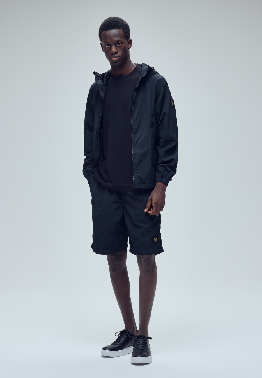ブラックのTシャツ・ブラックのハーフパンツ・ブラックのスニーカーを着用した男性