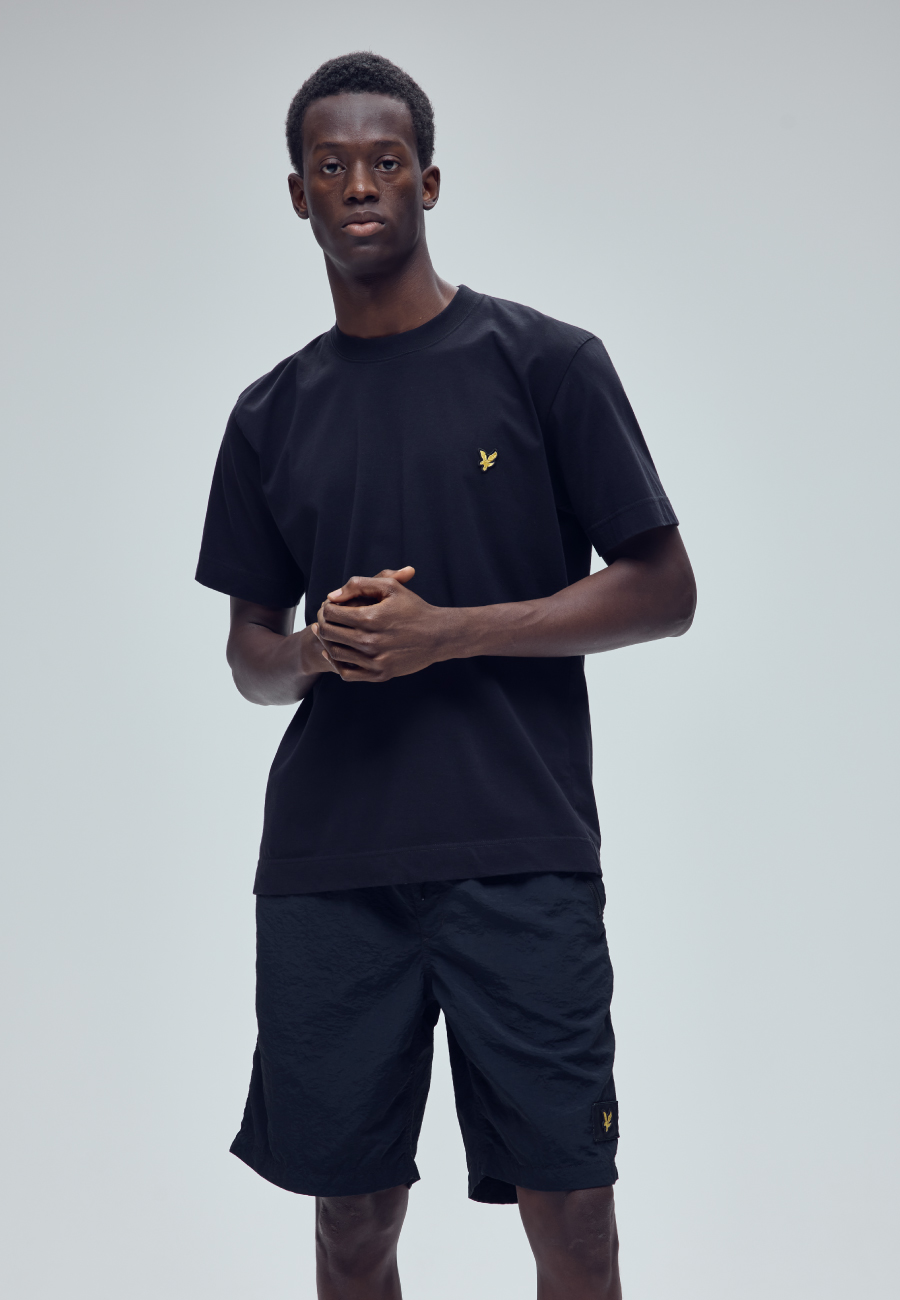 ブラックのTシャツ・ブラックのハーフパンツ・ブラックのスニーカーを着用した男性
