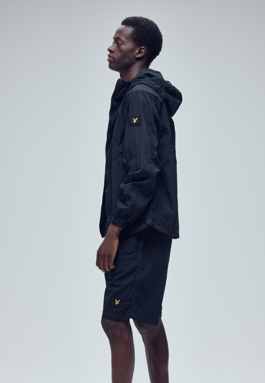 ブラックのTシャツ・ブラックのハーフパンツ・ブラックのスニーカーを着用した男性