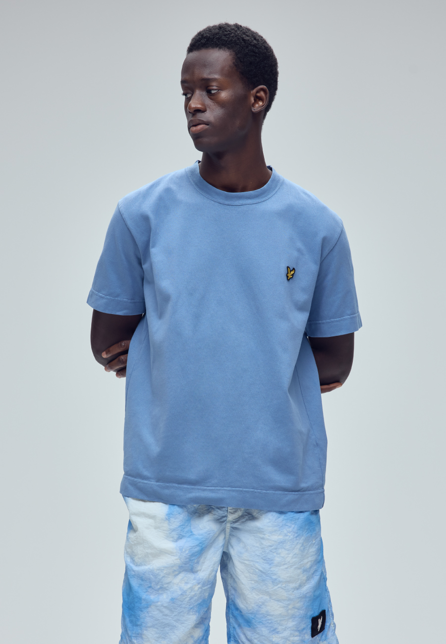 空のような模様のブルゾン・パンツ・ベージュのTシャツを着用した男性